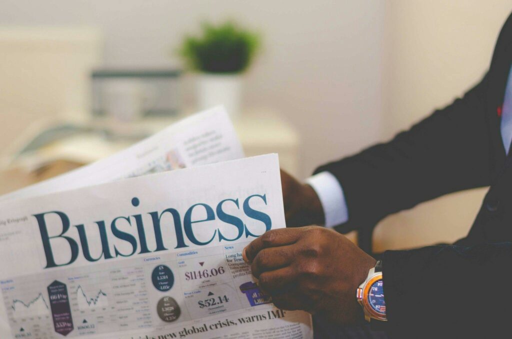 Close-up of a person in a suit reading the Business section of a newspaper.