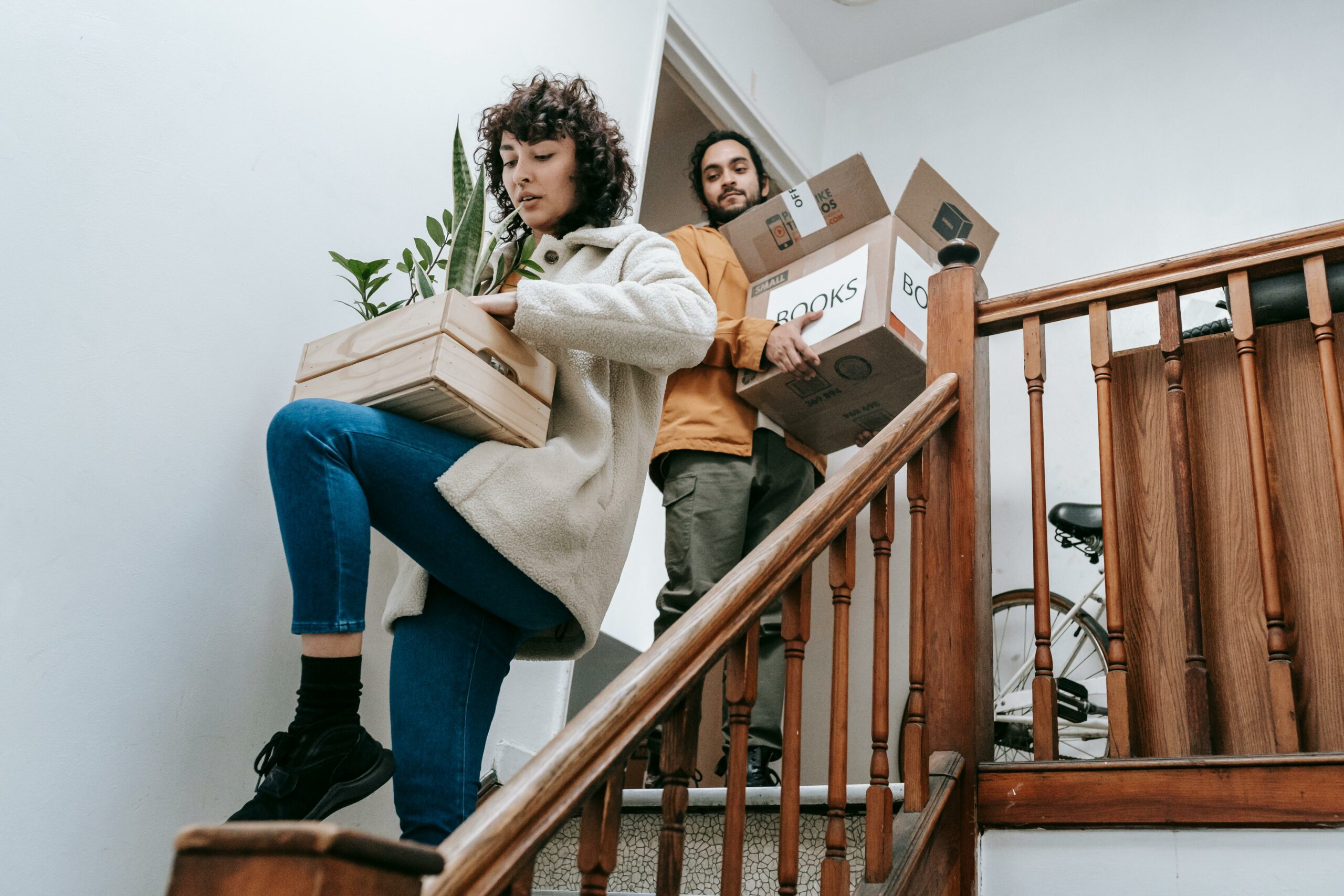 A couple carrying boxes up the stairs, indicating a move into a new home.