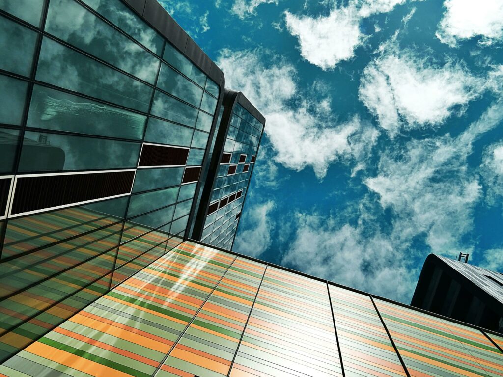 Upward view of a modern skyscraper with reflective glass against a backdrop of a cloudy sky.