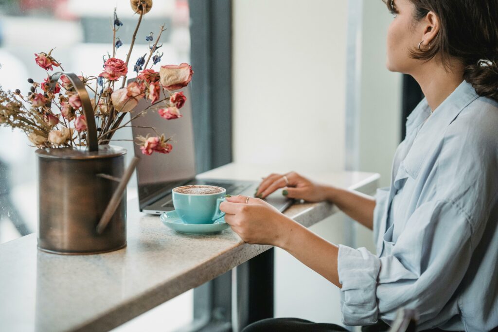 A person at a cafe counter with a laptop and a cup of coffee, symbolizing a break in their busy day.