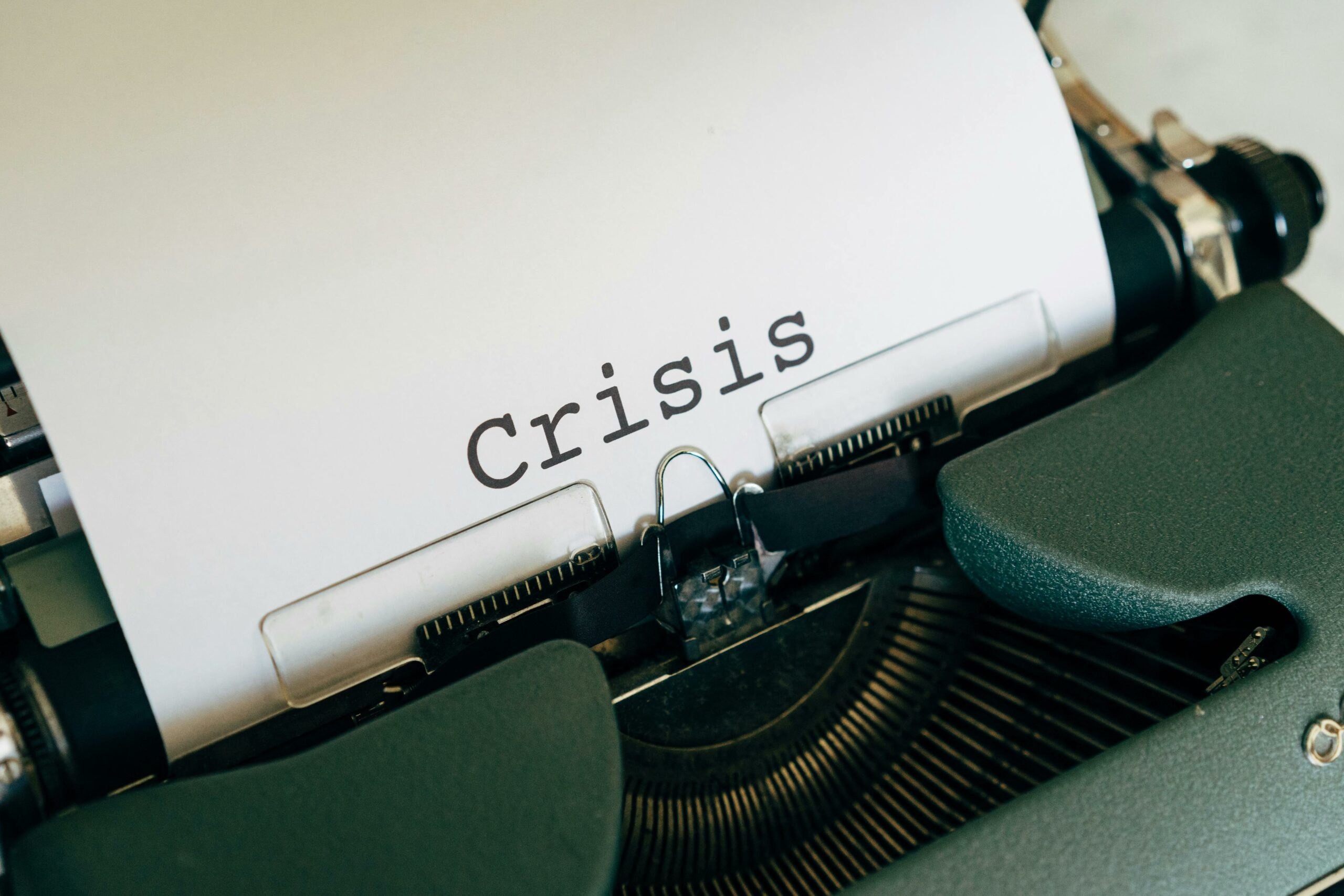 Close-up of the word 'Crisis' typed on a paper in a vintage typewriter.