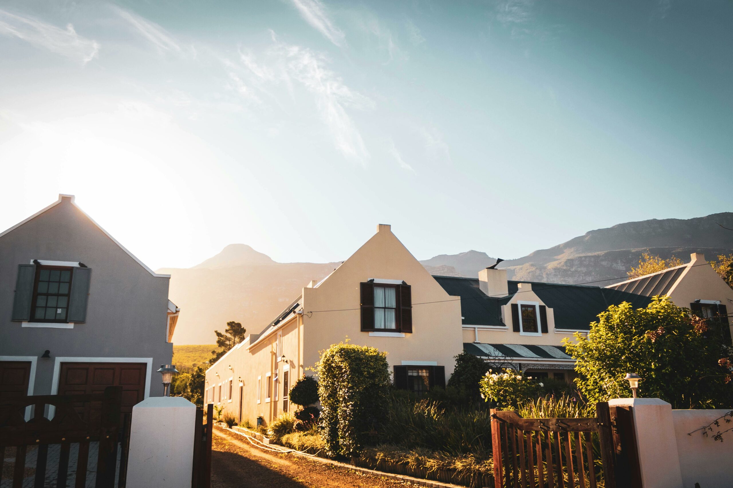Sunrise over a picturesque suburban street with modern houses against a mountain backdrop.