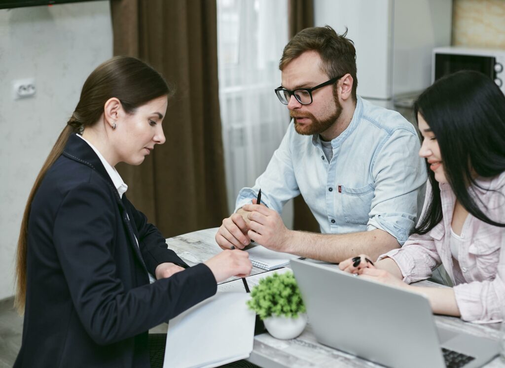 Two professionals consulting with a Asset Finance Broker at a desk with a laptop.