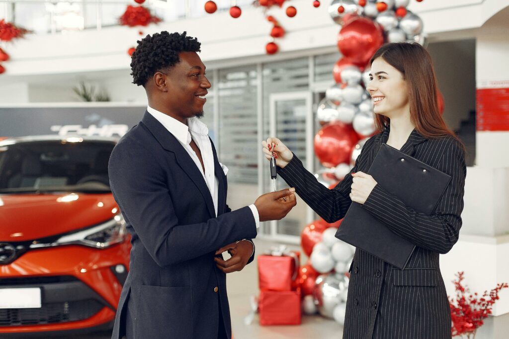 A person holding car keys in front of a new car, symbolizing obtaining a car loan despite having bad credit.